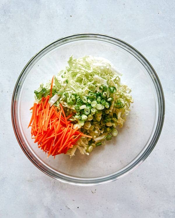 Adding veg to a bowl to make okonomiyaki recipe.