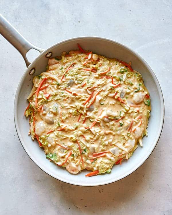 Okonomiyaki pancake batter in an oiled hot skillet.