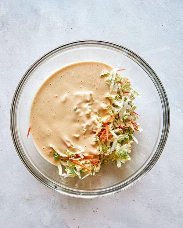 Mixing vegetables and batter in a glass bowl.