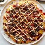 Okonomiyaki on a plate with fork next to it.