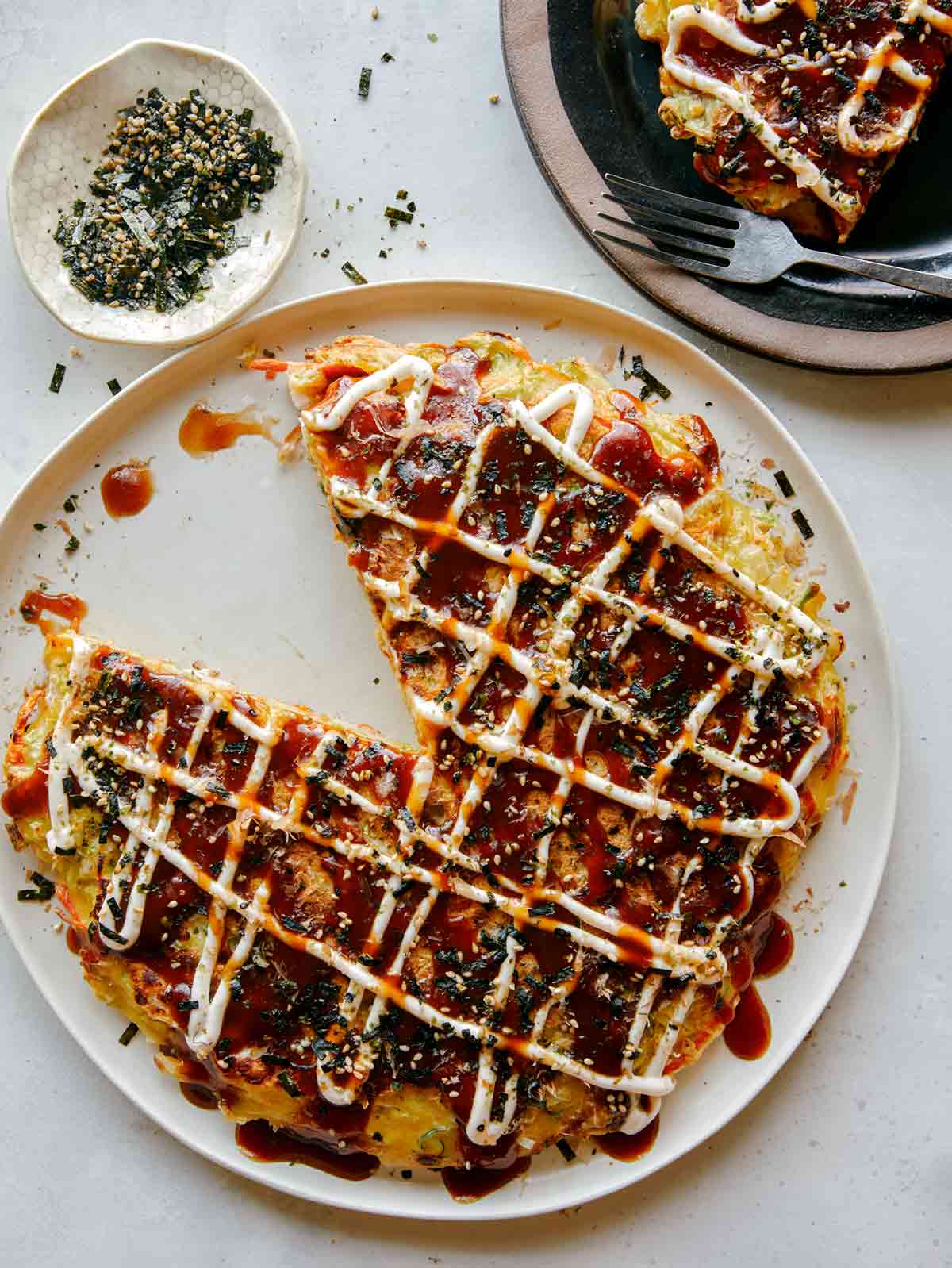 Okonomiyaki with a slice out and furikaki on the side.