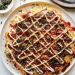 Okonomiyaki on a plate with fork next to it.