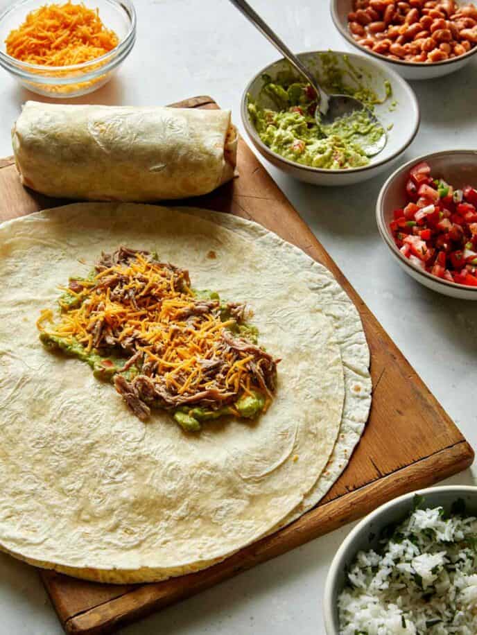 The process of making a pork burrito with a tortilla.