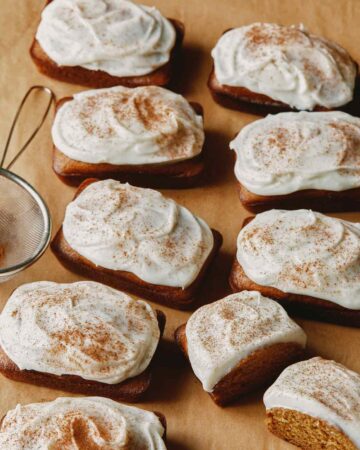 Pumpkin bars with cream cheese frosting on parchment.