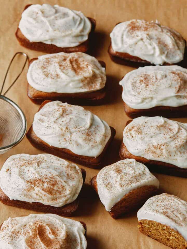 Pumpkin bars with cream cheese frosting on parchment.