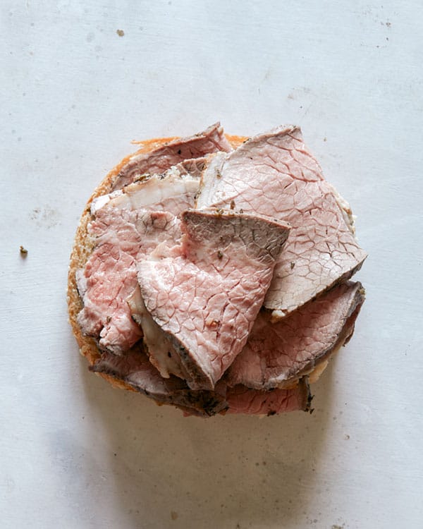 Roast beef on top of a hamburger bun.