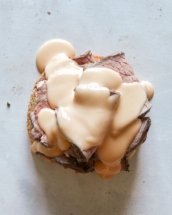 Cheese sauce smothering a roast beef sandwich.