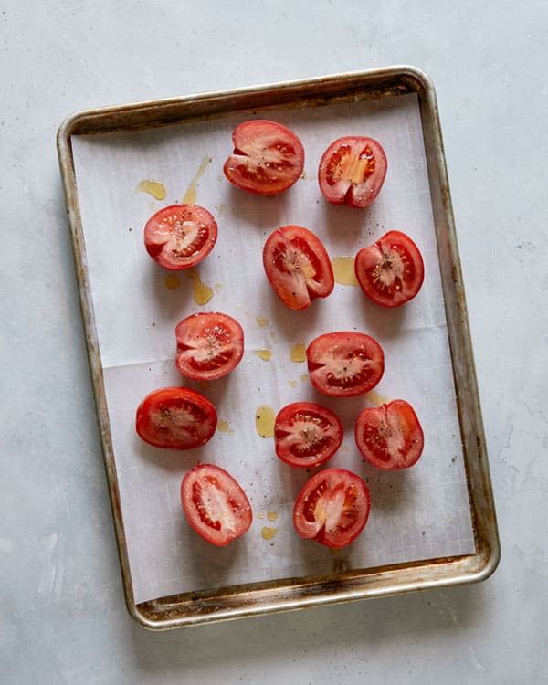 Tomatoes on a baking sheet about to be roasted to make tomato soup. 
