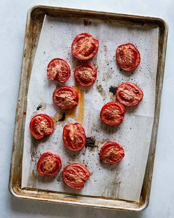 Roasted roma tomatoes on a baking sheet.