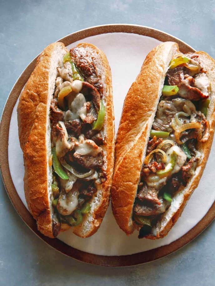 Two Philly Cheesesteak sandwiches on a plate. 