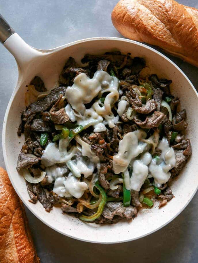 Philly cheesesteak in a skillet with melted cheese. 
