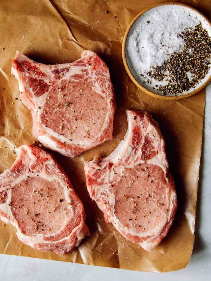 Pork chops seasoned on a piece of butcher paper. 