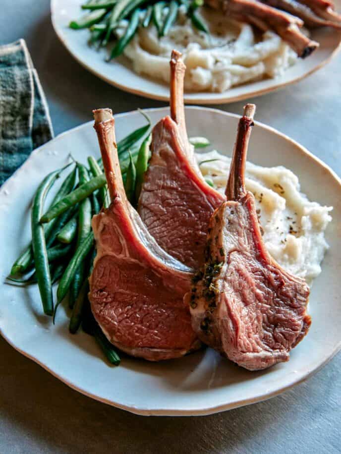 Rack of lamb plated with green beans and mashed potatoes.