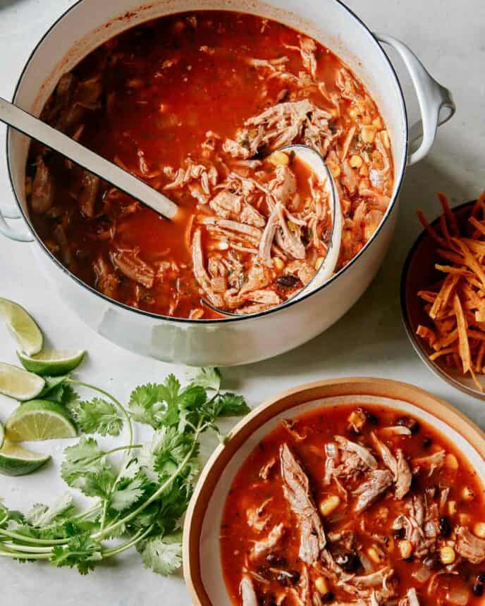 Tortilla soup being served into some bowls and garnished. 