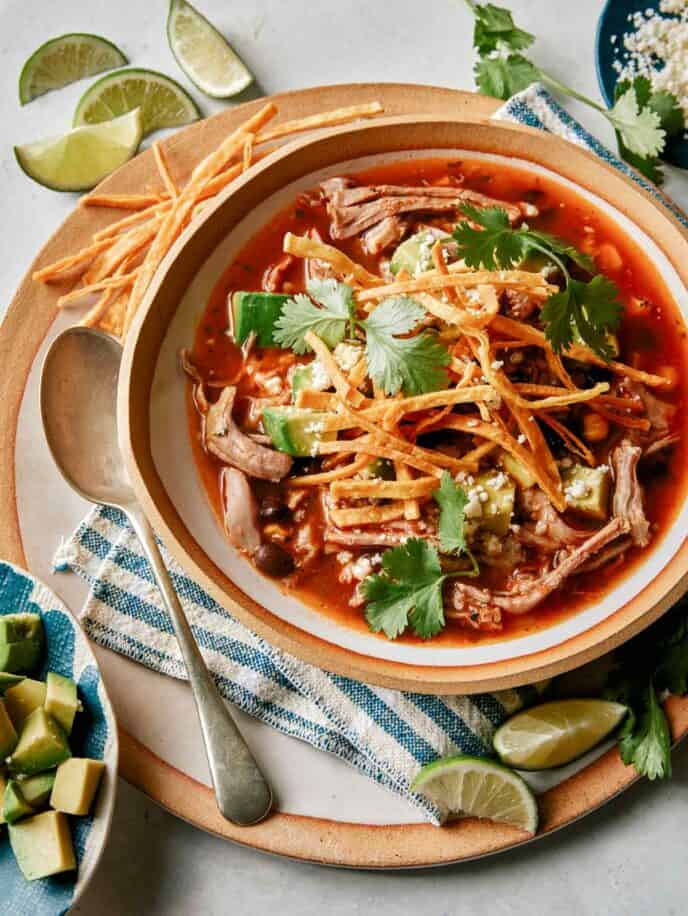 Tortilla soup recipe in a bowl with lime wedges on the side. 