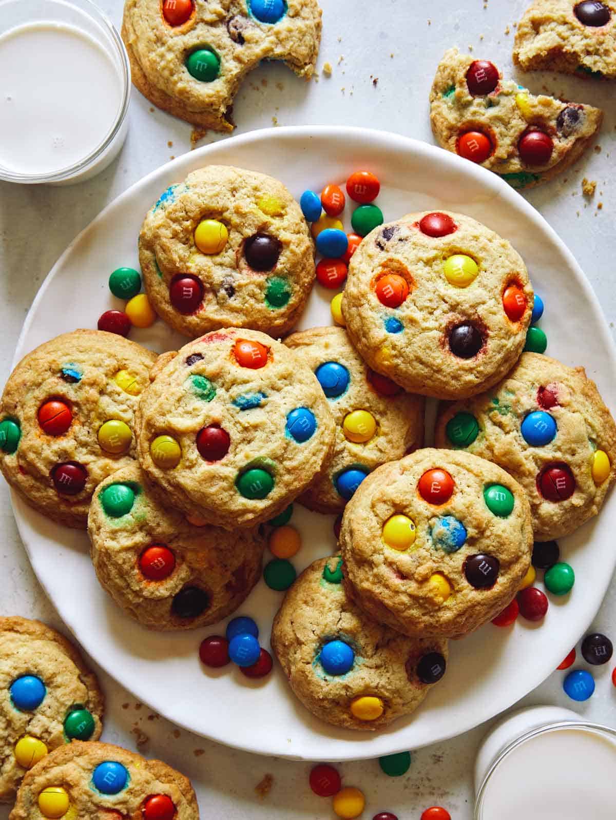 M&M cookie recipe on a plate with milk on the side. 