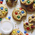 M&M cookies being eaten with a glass of milk.