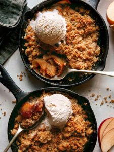 Apple crisps baked in cast iron skillets with ice cream on top.