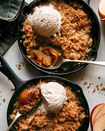 Apple crisps baked in cast iron skillets with ice cream on top.