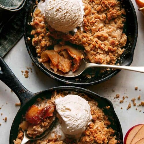 Apple crisps baked in cast iron skillets with ice cream on top.