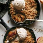 Two apple crisps being served with ice cream.