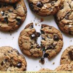 Brown butter chocolate chip cookies with one broken in half.