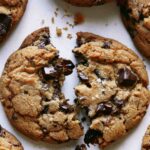 Brown butter chocolate chip cookies with one broken in half.