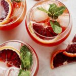 Blood orange shandy recipes being made in cocktail glasses.