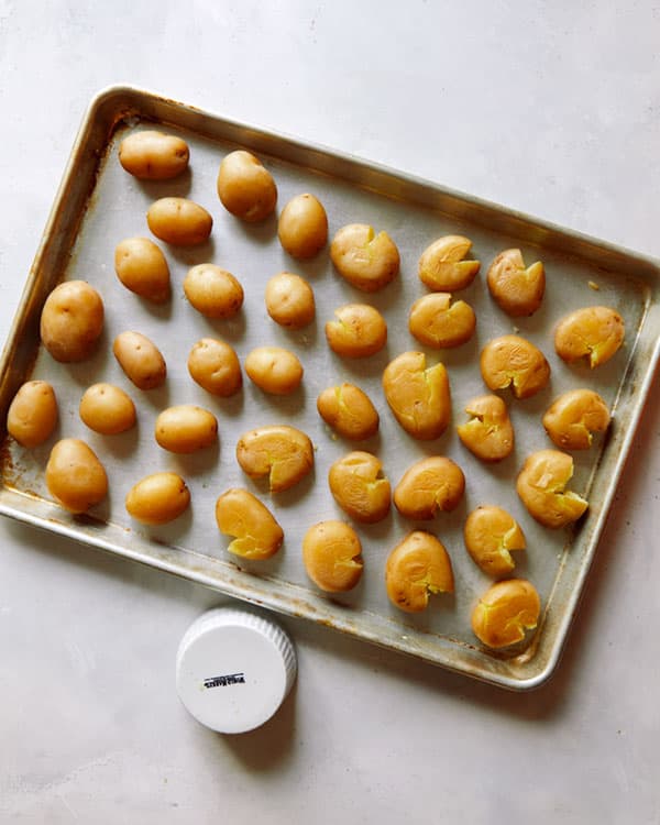 Potatoes gently smashed on a baking sheet.