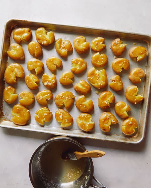 Smashed potatoes being brushed with garlic butter.