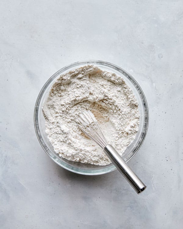 Flour combined in a glass bowl with a whisk. 