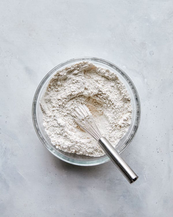 Flour combined in a glass bowl with a whisk.