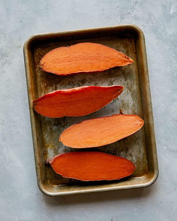 Roasted sweet potatoes cut in half on a cutting board.