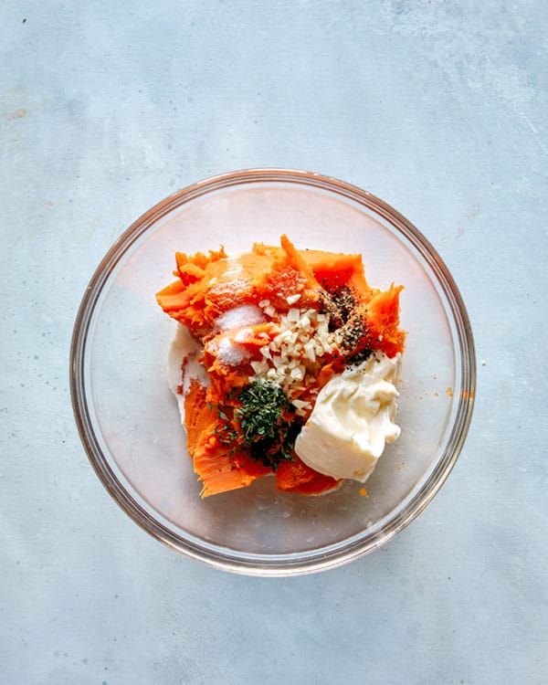 Roasted sweet potatoes with herbs and sour cream in a bowl. 