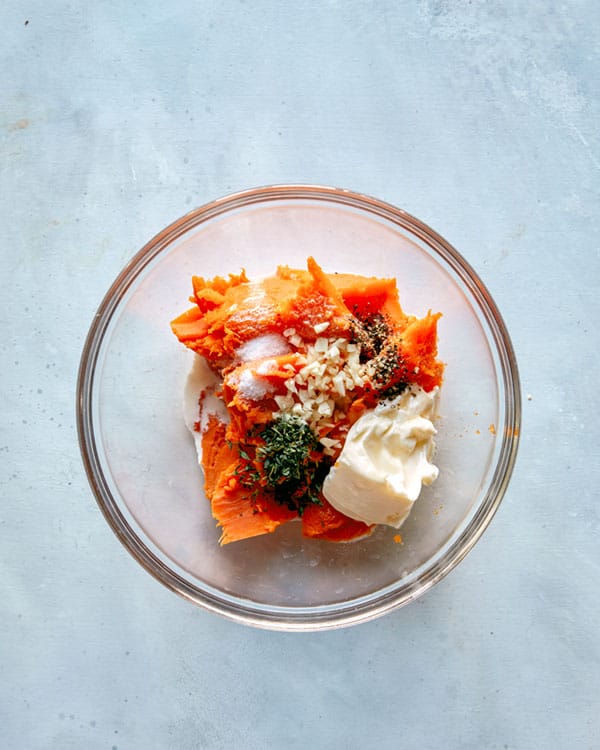 Roasted sweet potatoes with herbs and sour cream in a bowl.