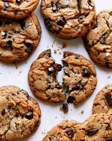 Brown butter chocolate chip cookies with one broken in half.