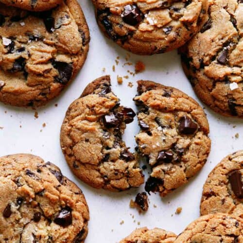 Brown butter chocolate chip cookies with one broken in half.