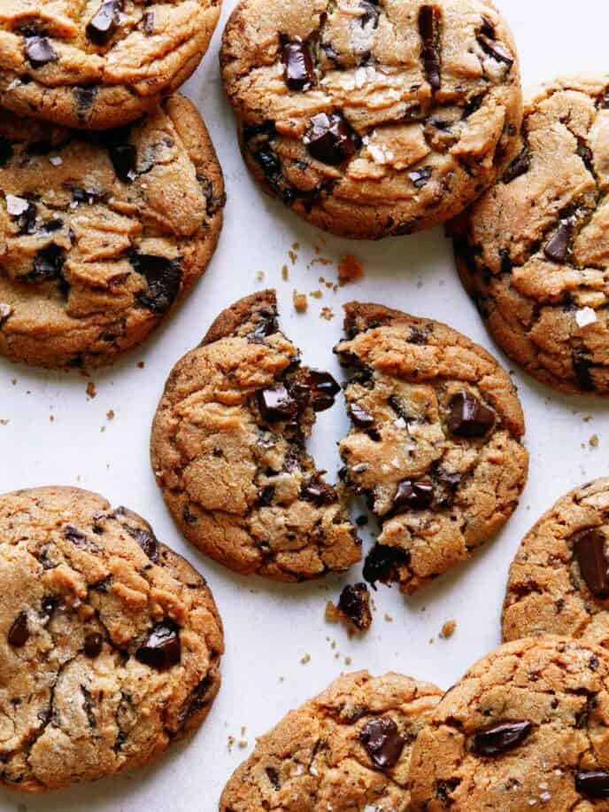 Brown butter chocolate chip cookies with one broken in half. 