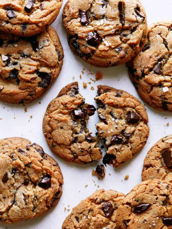 Brown butter chocolate chip cookies with one broken in half.