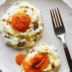 Cloud eggs on a plate with a yolk broken.