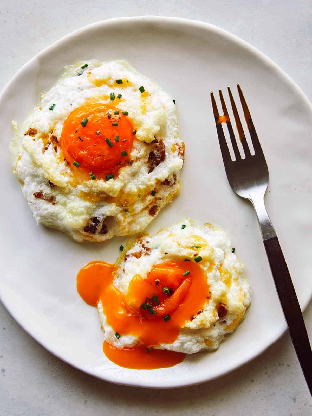 Cloud Eggs on a plate with a yolk popped.