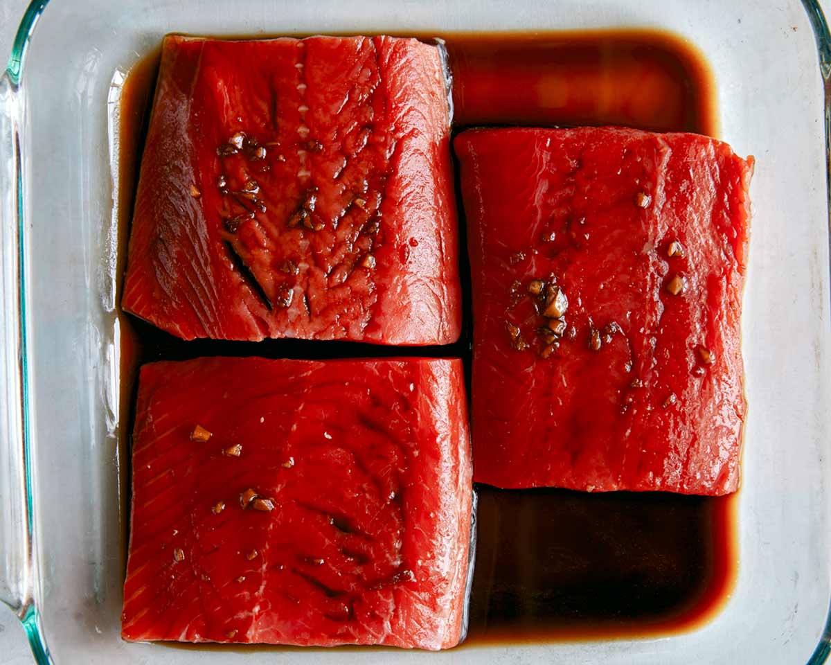 Salmon marinating in a dish with teriyaki sauce. 