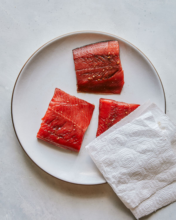 Teriyaki salmon being pat dry with a paper towel. 