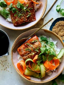 Teriyaki salmon recipe in two bowls with sesame seeds on the side.