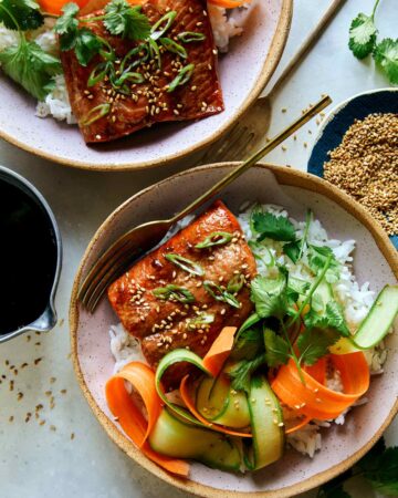 Teriyaki salmon recipe in two bowls with sesame seeds on the side.