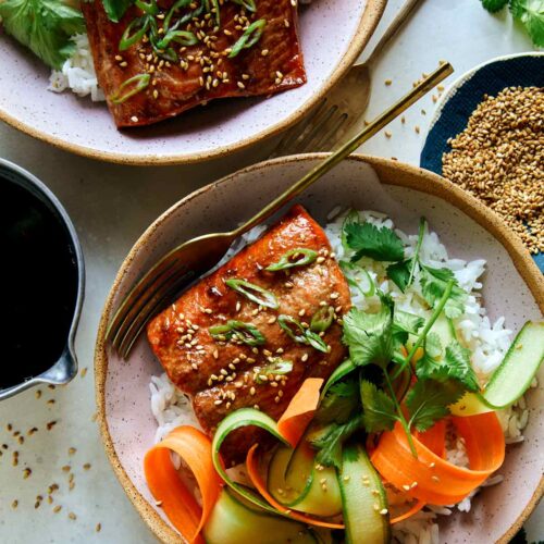 Teriyaki salmon recipe in two bowls with sesame seeds on the side.
