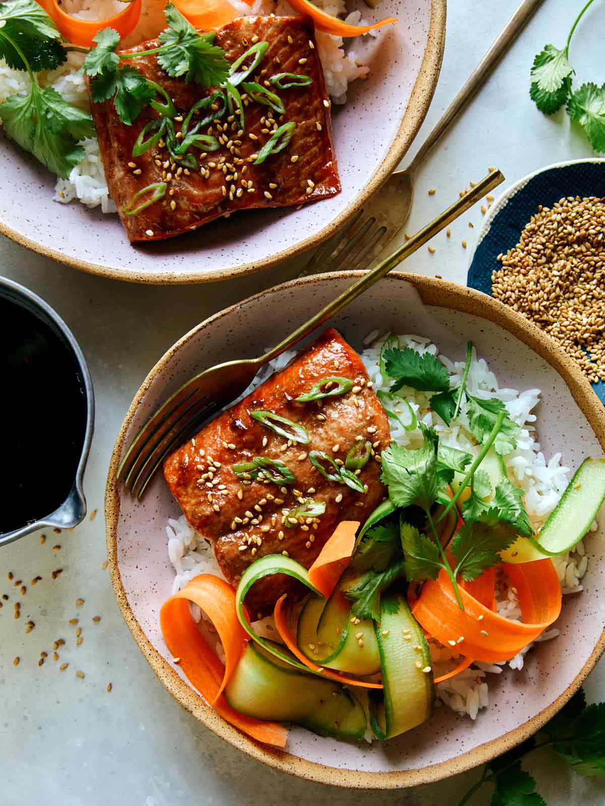 Teriyaki salmon recipe in two bowls with sesame seeds on the side. 