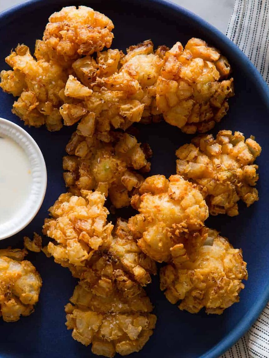 Super Bowl appetizer of Baby bloomin' onions on a dark blue plate with a side of buttermilk ranch dipping sauce.