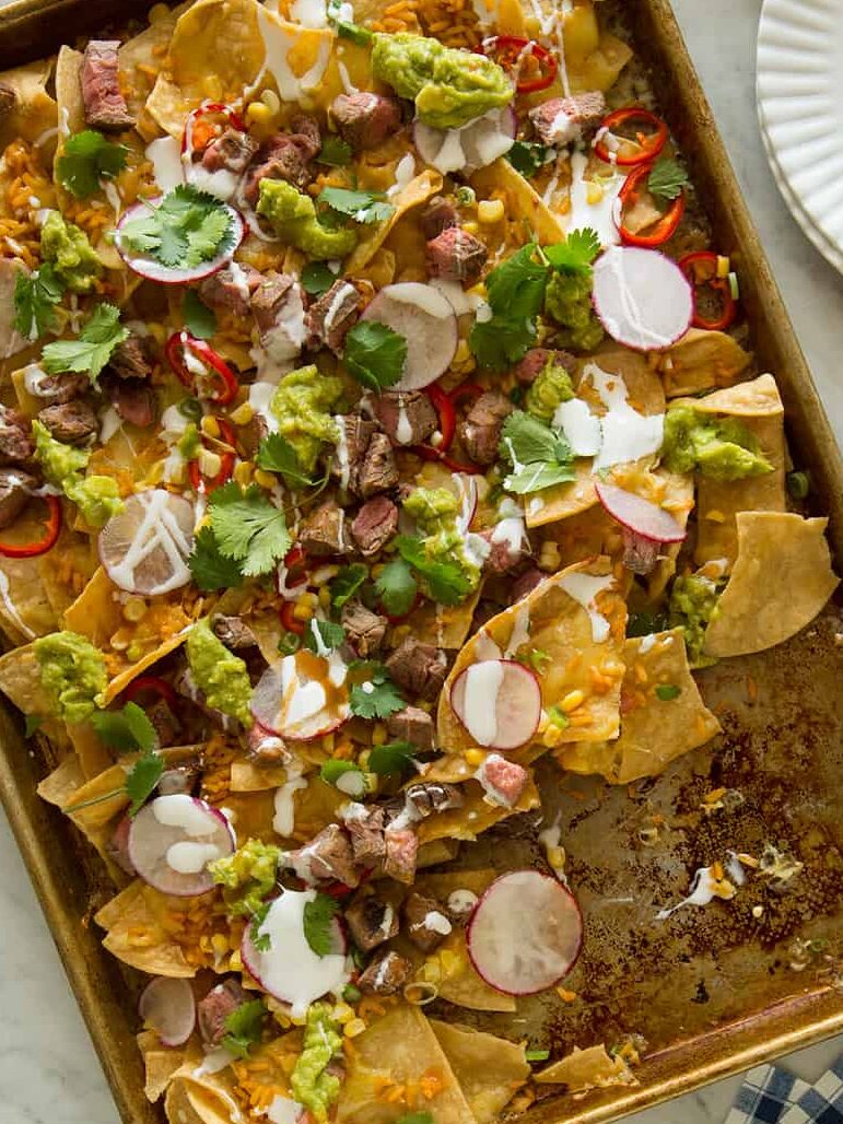 Carne asada nachos with servings on small plates, for a Super Bowl snack. 