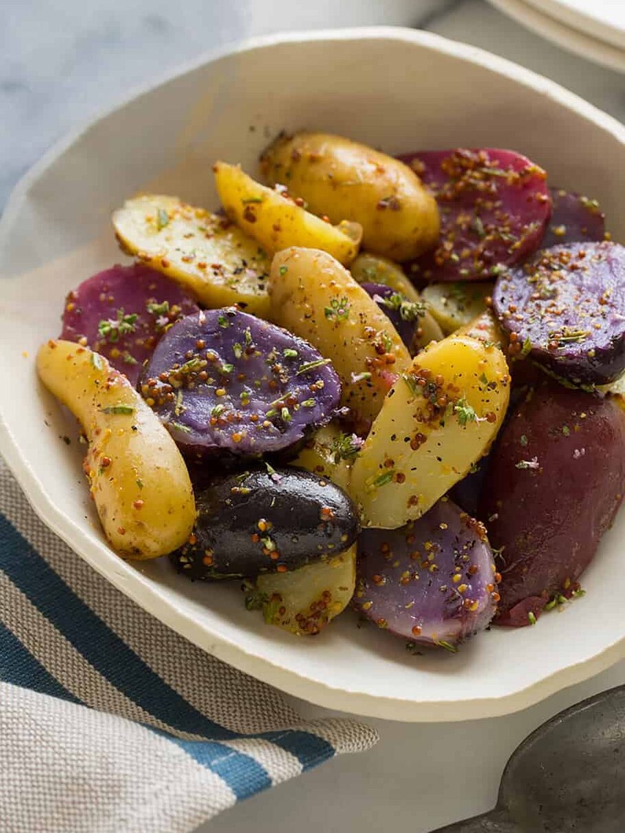 A bowl of warm German potato salad with a blue striped napkin.